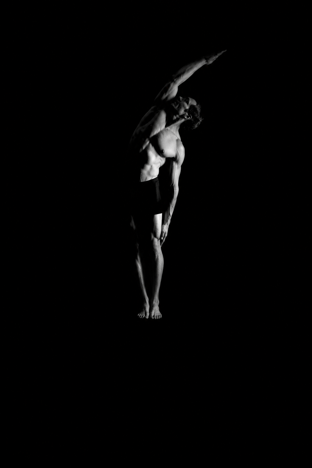 Athlete mid recovery stretch, studio light, grayscale