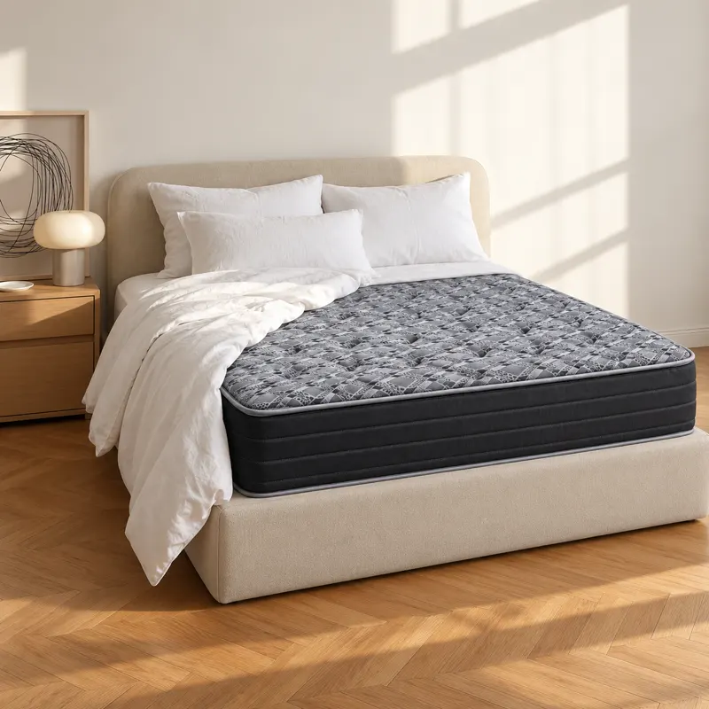 Full mattress with a gray patterned quilted top on an upholstered bed, in soft morning light